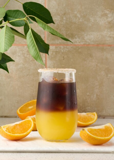 Kalter Kaffee mit Orangensaft in einem transparenten Glas und Orangenscheiben