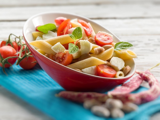 Kalter Nudelsalat mit in Scheiben geschnittenen Tomaten, Mozzarella und Bohnen