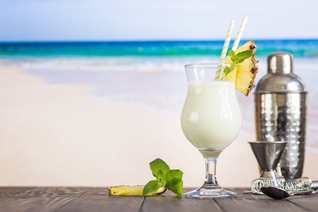 Kalter Pina Colada Cocktail in einem Glas am Strand mit Seestückhintergrund