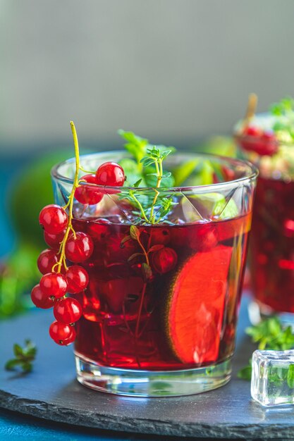 Kalter roter Cocktail mit Reis, Limette, Minze, Thymian und Eis in einem Glas auf einem dunkeln Betonboden Sommergetränke und alkoholische Cocktails Alkoholic Cocktail Reis Mojito