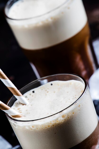 Foto kalter, schaumiger frappe-kaffee in großen gläsern auf braunem hintergrund, selektiver fokus