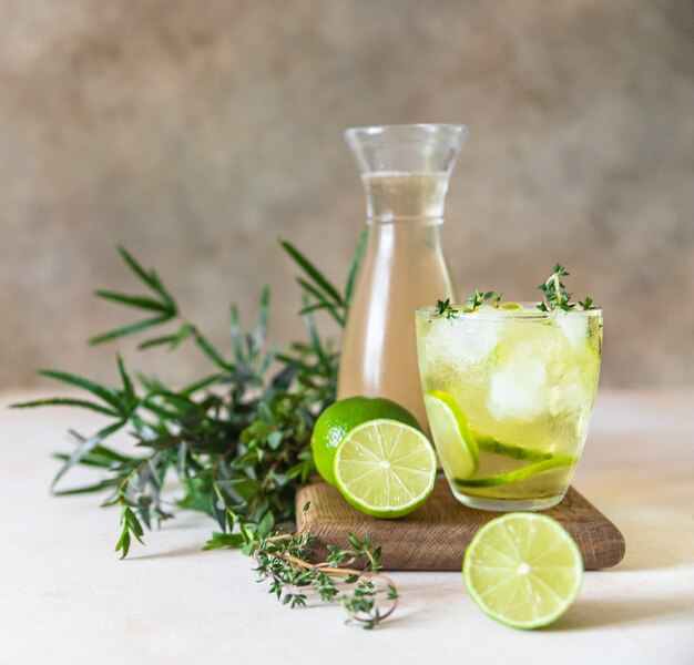 Kaltes erfrischendes Sommergetränk oder Limonade mit Limette und Thymian auf Betonoberfläche