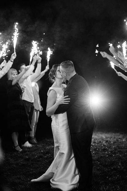 Foto kaltes feuer aus kuchenkerzen und feuerwerkskörpern in den händen der menschen um das brautpaar