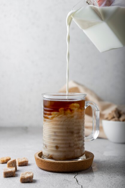 Kaltes Getränk mit Kaffee und Milch. transparenter Glasbecher auf hellem Hintergrund. vertikale Position