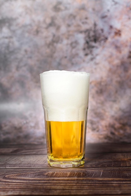 Foto kaltes handwerksbier gießt aus der flasche auf den holztisch