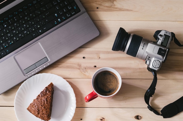 Foto kamera und laptop auf hölzernem hintergrund kaffee und kuchen