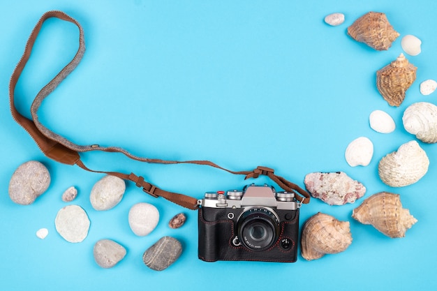 Kamera und Muscheln auf blauem Hintergrund. Hintergrund für den Reisenden