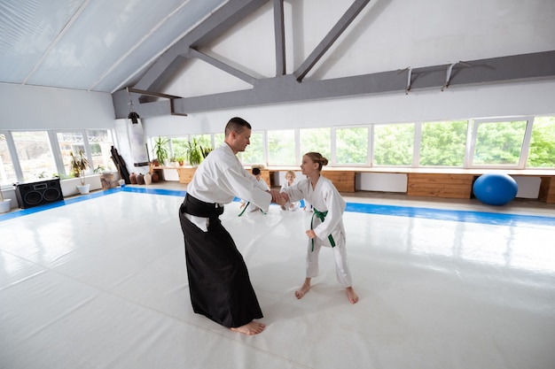 Kampf mit Trainer. Mädchen mit weißem Kimono mit grünem Gürtel und Kampf mit Trainer
