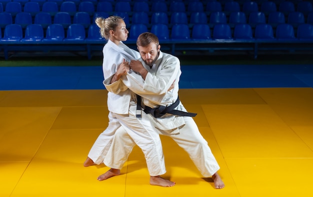 Kampfkunst. Sparsame Portner. Sport Mann und Frau im weißen Kimono Zug Judo wirft und fängt in der Sporthalle