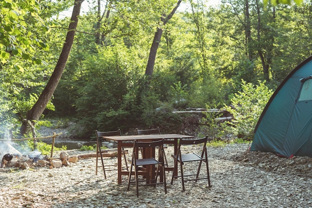 Kampieren am Strand des blauen Zeltlagertisches und der Stühle des Gebirgsflusses im Wald