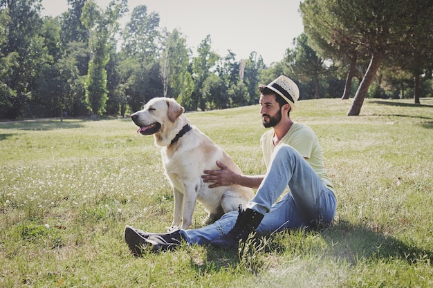 Kanadischer Labrador-Hund ruht sich an einem sonnigen Tag mit seinem Besitzer im Park aus