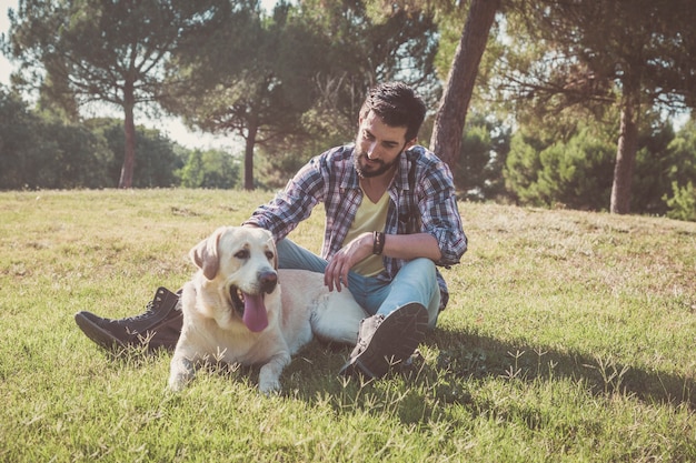 Kanadischer Labrador-Hund ruht sich an einem sonnigen Tag mit seinem Besitzer im Park aus