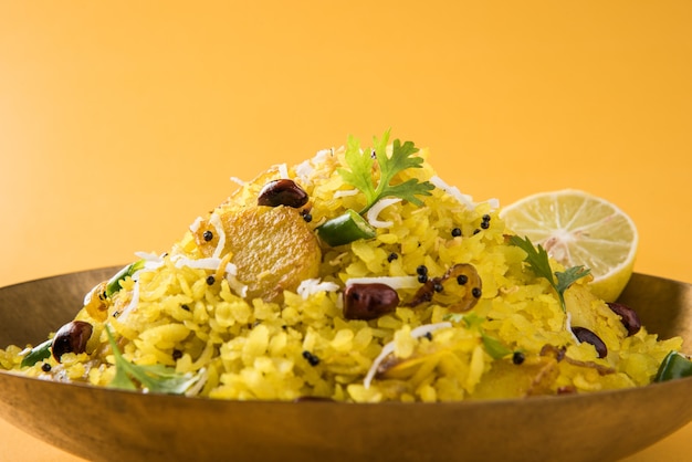 Kande Pohay OU Aloo Poha é uma receita popular de café da manhã indiano feita com arroz achatado, geralmente servido com chá quente. Servido em uma tigela. Foco seletivo