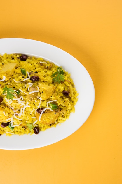 Kande Pohay OU Aloo Poha é uma receita popular de café da manhã indiano feita com arroz achatado, geralmente servido com chá quente. Servido em uma tigela. Foco seletivo