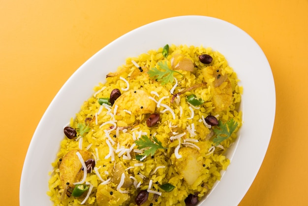 Kande Pohay OU Aloo Poha é uma receita popular de café da manhã indiano feita com arroz achatado, geralmente servido com chá quente. Servido em uma tigela. Foco seletivo