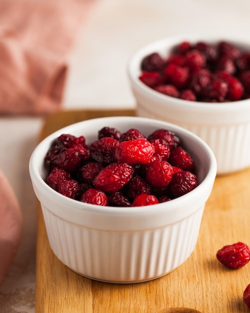 Kandierte Preiselbeeren, getrocknete Preiselbeeren Nahaufnahme in einer weißen Schüssel auf einem Holzbrett