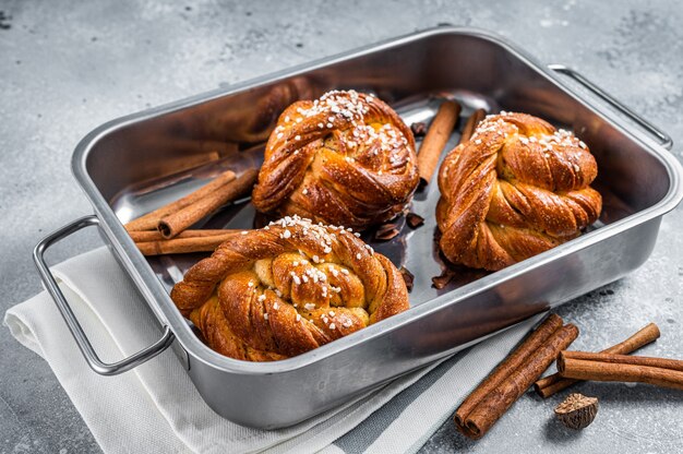 Kanelbullar - Schwedische Zimtschnecken in Auflaufform. Grauer Hintergrund. Ansicht von oben.