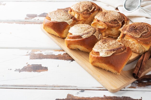 Kanelbulle Zimtschnecken mit Buttercreme auf einem rustikalen Holztisch. Hausgemachtes frisches Gebäck.