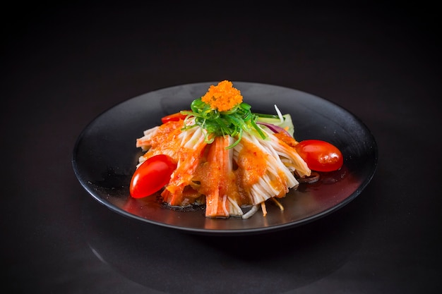 Foto kani salada coberto wakame, comida japonesa em fundo preto, comida saudável
