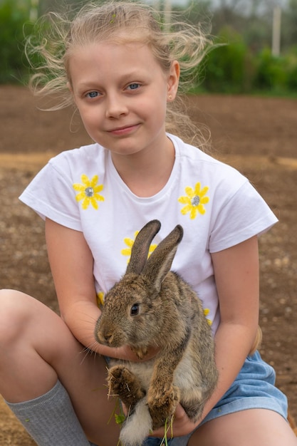 Kaninchensommertag im freien Mädchen kleines weißes spielendes Häschen ostern von glücklicher Kindheit für Gras für