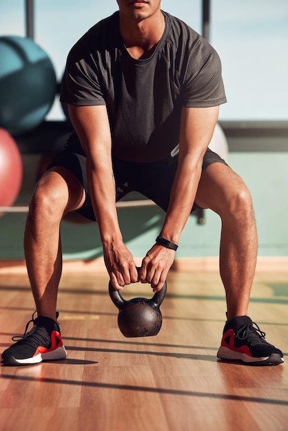 Kannst du spüren, wie deine Oberschenkel brennen Aufnahme eines Mannes, der im Fitnessstudio mit Kettlebells trainiert