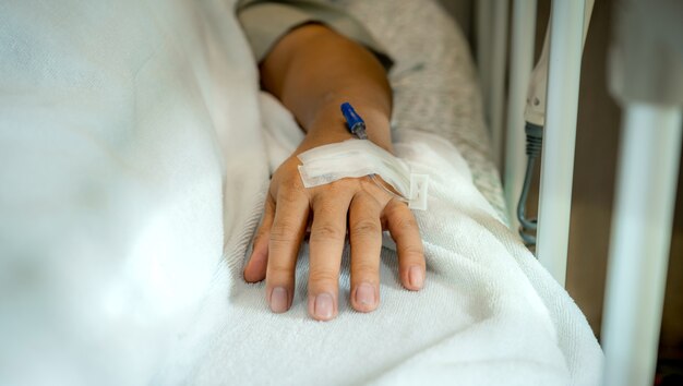 Kanüle auf den männlichen Patienten Hand auf dem Bett in der Station