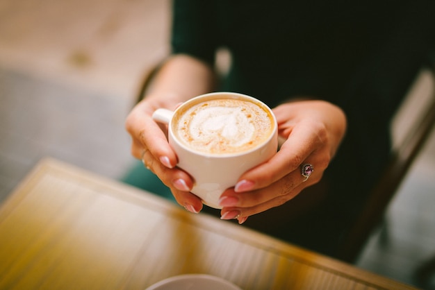 Kappe Kaffee, Cappuccino, Latte in Frauenhänden schließen