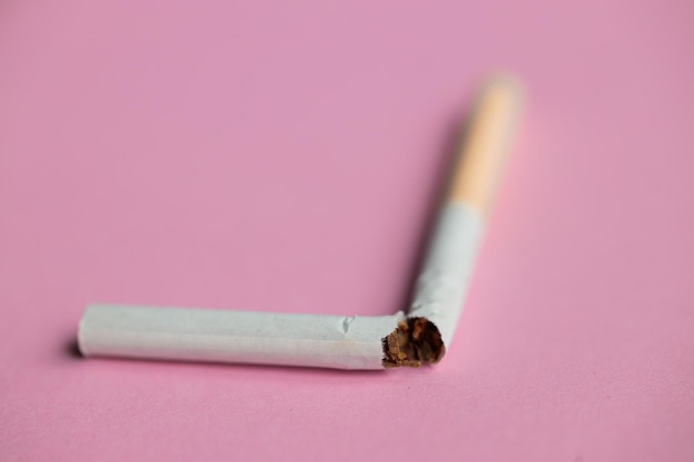 Kaputte Zigarette auf rosa Hintergrund