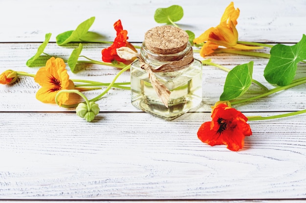 Kapuzinerkresse-Kräuteröl von Blumen verlässt Samen Kapuzinerkresse-Extrakt in Flasche auf Holzhintergrund