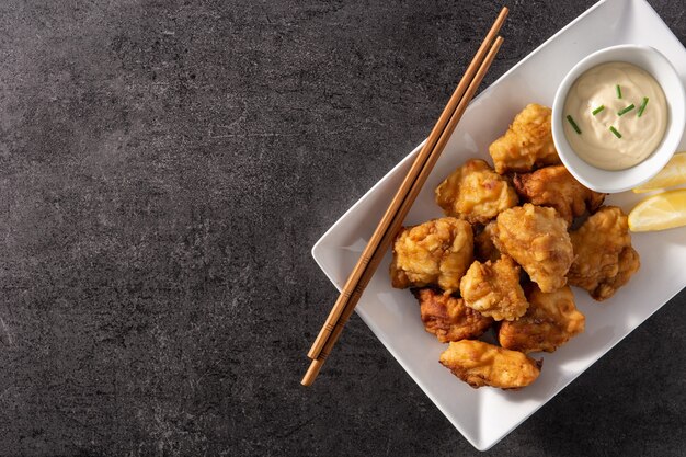 Karaage de pollo picante sobre fondo de pizarra negra