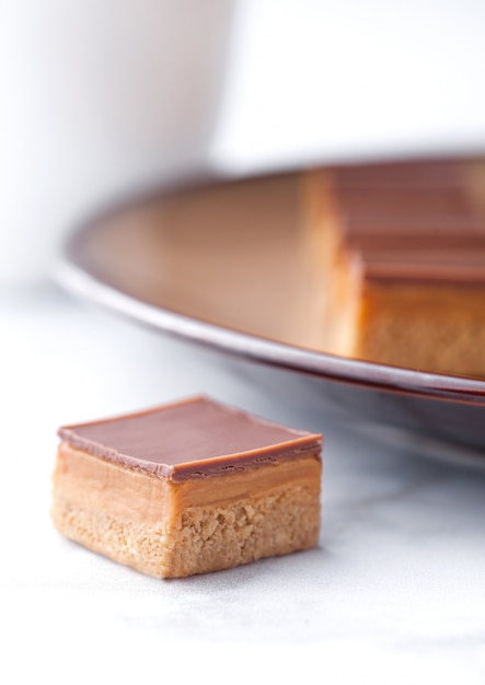 Foto karamell- und keksshortcake beißt nachtisch auf brauner platten- und kaffeetasse