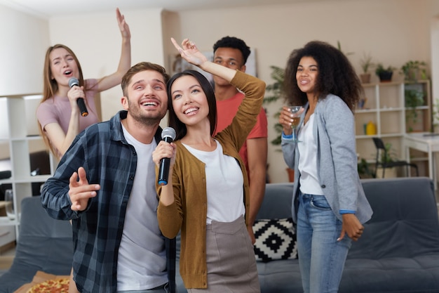 Karaoke-Party junges glückliches Paar oder Freunde, die Mikrofon halten und beim Spielen zusammen singen