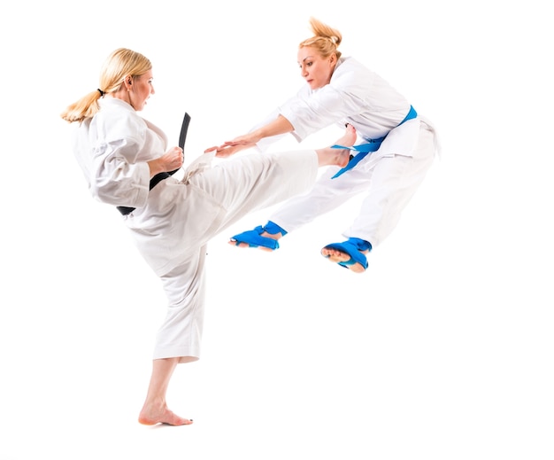 Karate de chicas rubias lindas se dedican a la formación en un kimono sobre un fondo blanco.