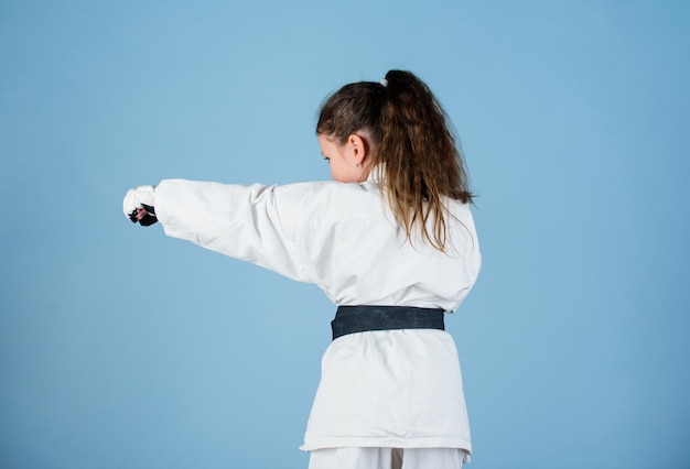 Karate-sport-konzept selbstverteidigungsfähigkeiten karate vermittelt selbstvertrauen starkes und selbstbewusstes kind sie ist gefährlich mädchen kleines kind im weißen kimono mit gürtel karate-kämpfer bereit zu kämpfen