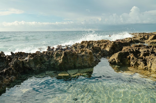 Karibisches Meer Korallenriffe Welle brechen am Ufer Felsen Riviera Maya Meereslandschaft Mexiko Sonnenschirm