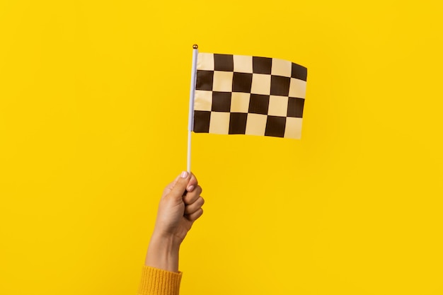 Karierte Flagge in der Hand über gelbem Hintergrund