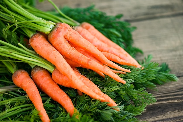 Karotte auf Holztischhintergrund Frische und süße Karotten zum Kochen von Obst und Gemüse für das Gesundheitskonzept Babykarotten Bund und Blatt