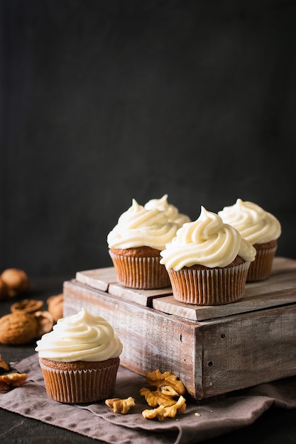 Karotten Cupcakes oder Muffins mit Nüssen auf schwarz, vertikal