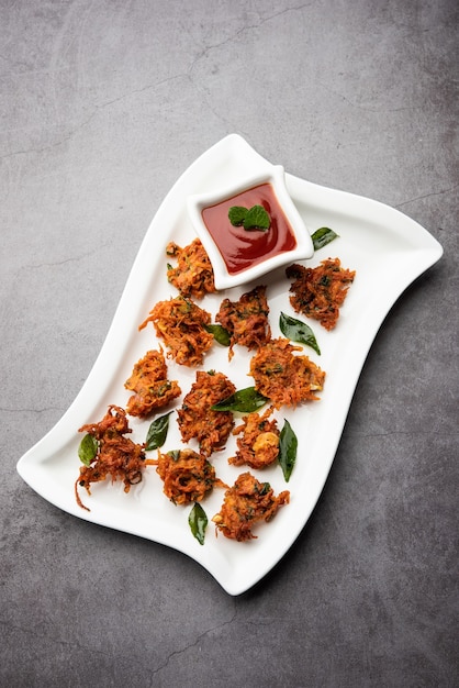 Karottenkrapfen oder Gajar ke pakore oder pakode oder bajji oder bhaji, indischer Snack serviert auf einem Teller mit Tomatenketchup