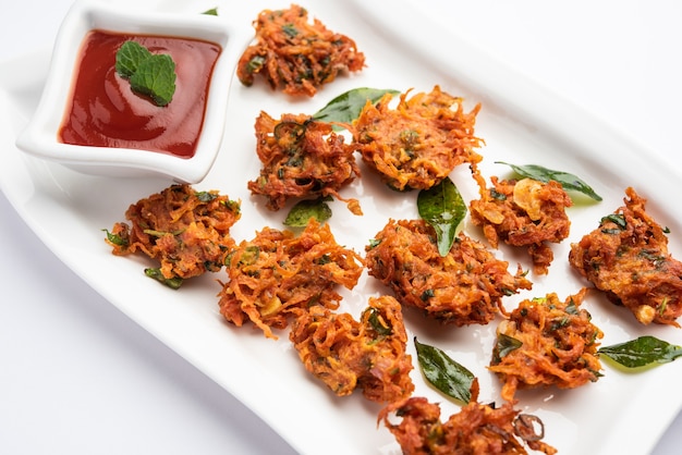 Karottenkrapfen oder Gajar ke pakore oder pakode oder bajji oder bhaji, indischer Snack serviert auf einem Teller mit Tomatenketchup