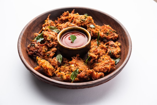 Karottenkrapfen oder Gajar ke pakore oder pakode oder bajji oder bhaji, indischer Snack serviert auf einem Teller mit Tomatenketchup