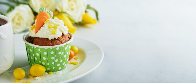 Karottenkuchen-Cupcakes für Ostern Karotten-Cupcakes mit Frischkäse-Zuckerguss dekoriert mit winzigen Marzipan-Karotten auf weißem Hintergrund Frohe Ostern und Frühlingsferien-Konzept Feiertage hausgemacht