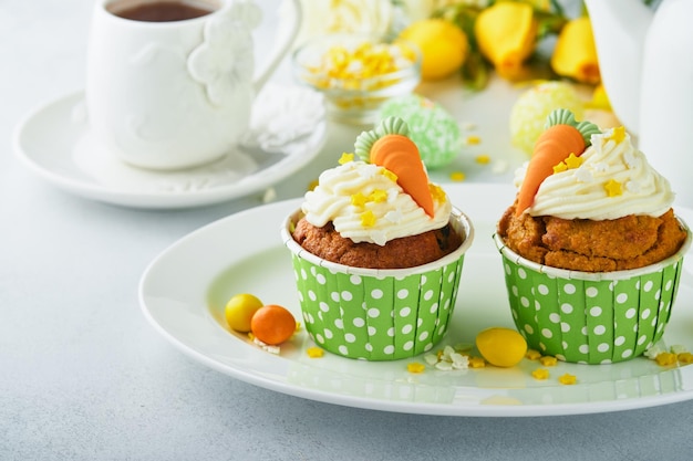 Karottenkuchen-Cupcakes für Ostern Karotten-Cupcakes mit Frischkäse-Zuckerguss, verziert mit winzigen Marzipan-Karotten auf weißem Hintergrund Frohe Ostern und Frühlingsferien-Konzept Feiertage hausgemachtes Dessert