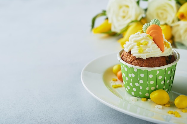 Karottenkuchen-Cupcakes für Ostern Karotten-Cupcakes mit Frischkäse-Zuckerguss, verziert mit winzigen Marzipan-Karotten auf weißem Hintergrund Frohe Ostern und Frühlingsferien-Konzept Feiertage hausgemachtes Dessert