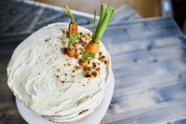 Karottenkuchen mit weißem Zuckerguss garniert mit frischen Karotten Ansicht von oben