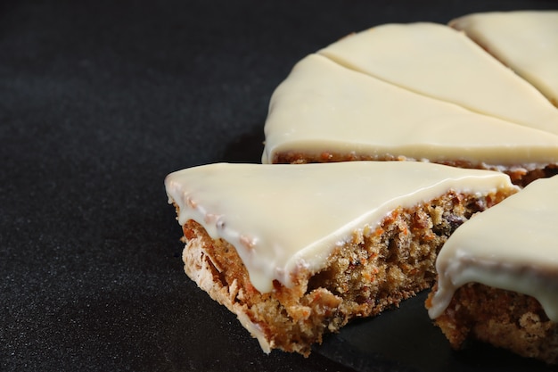 Karottenkuchen mit Zuckerguss auf dunklem Hintergrund schließen oben