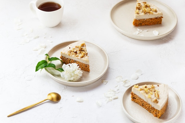 Karottenkuchenstücke mit Kokoscreme und Walnüssen auf Tellern zuckerfrei, gluten- und laktosefrei