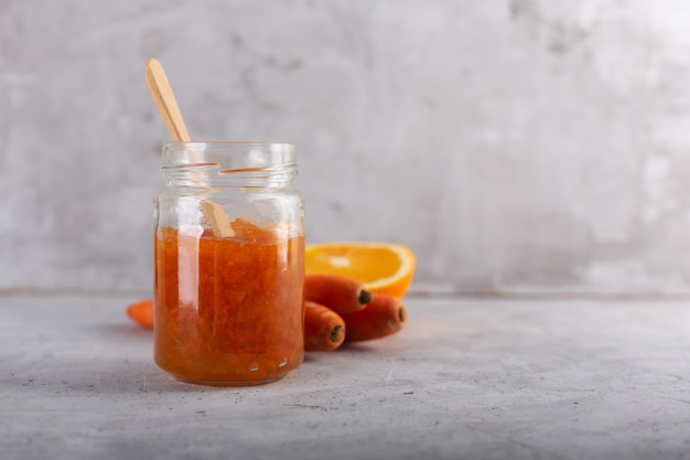 Karottenmarmelade mit Orangensaft auf grauem Hintergrund