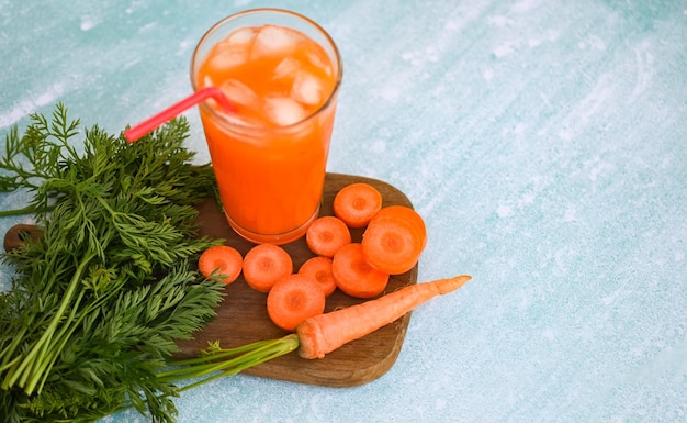 Karottensaft auf Holztischhintergrund Frische und süße Karottenscheiben zum Kochen von Obst und Gemüse für das Gesundheitskonzept Frischer Karottensaft auf Glas mit Eis im Sommer