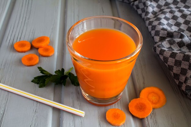 Karottensaft im Glas auf der grauen Holzoberfläche